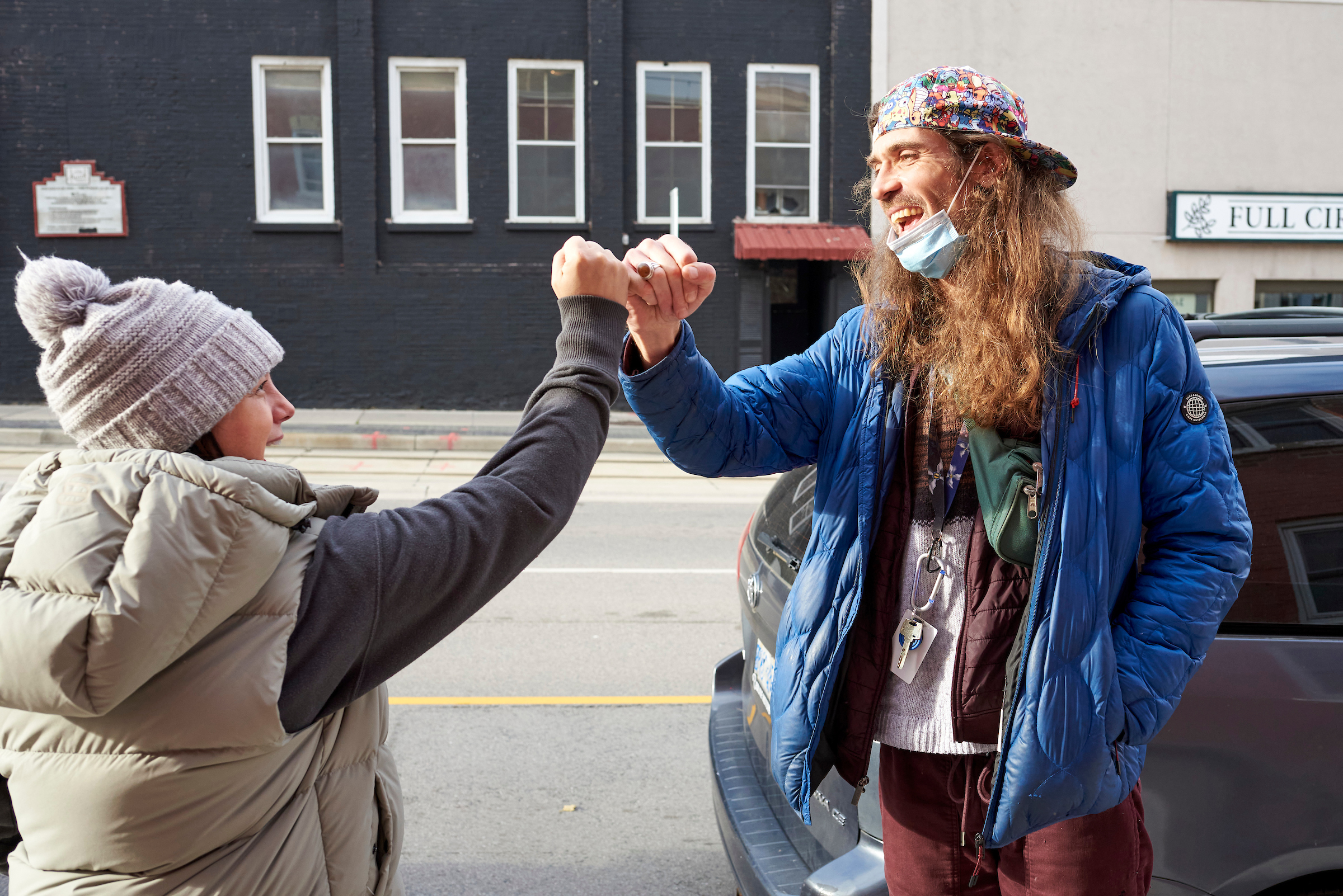 Two street outreach workers greeting each other with a fist bump, showcasing camaraderie and teamwork.