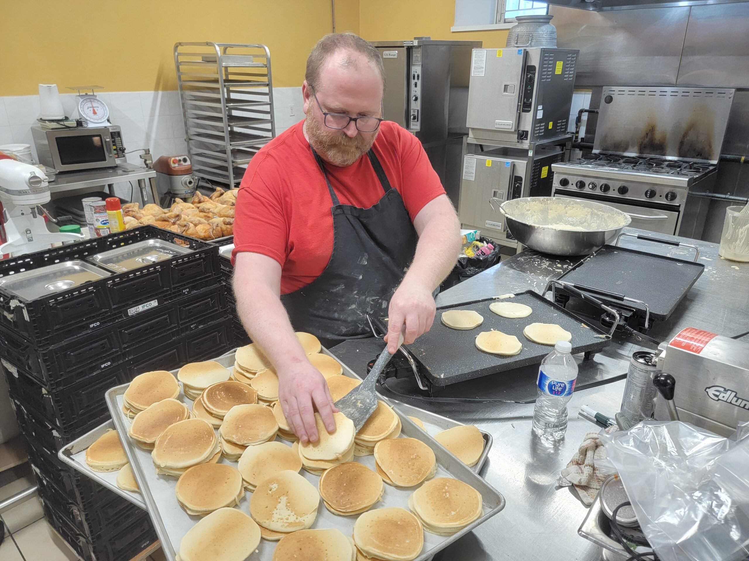 A volunteer flipping pancakes in the commissary kitchen at Maurita’s Kitchen, Kitchener, Ontario.