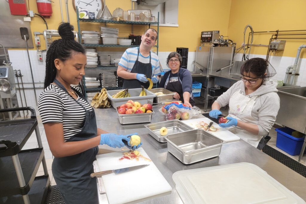 A group of volunteers peeling and chopping fresh produce in the commissary kitchen at Maurita’s Kitchen, Kitchener, Ontario.