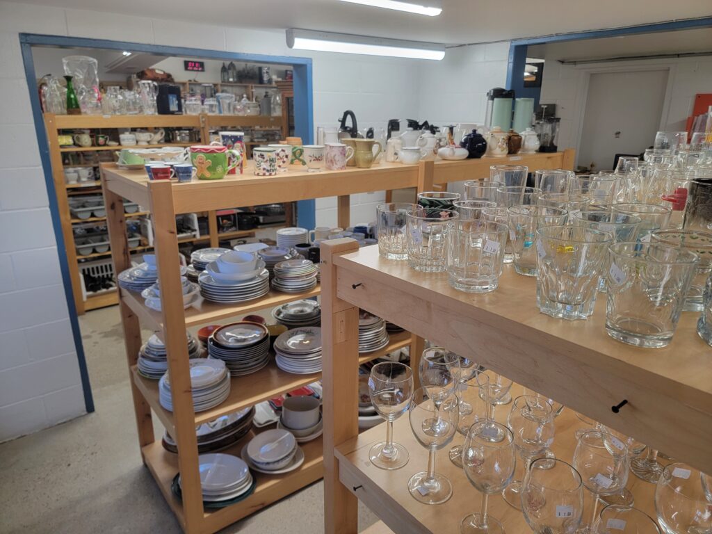 Shelves of glassware, dishes, and other housewares neatly arranged at Worth a Second Look, a used furniture store in Kitchener, Ontario.