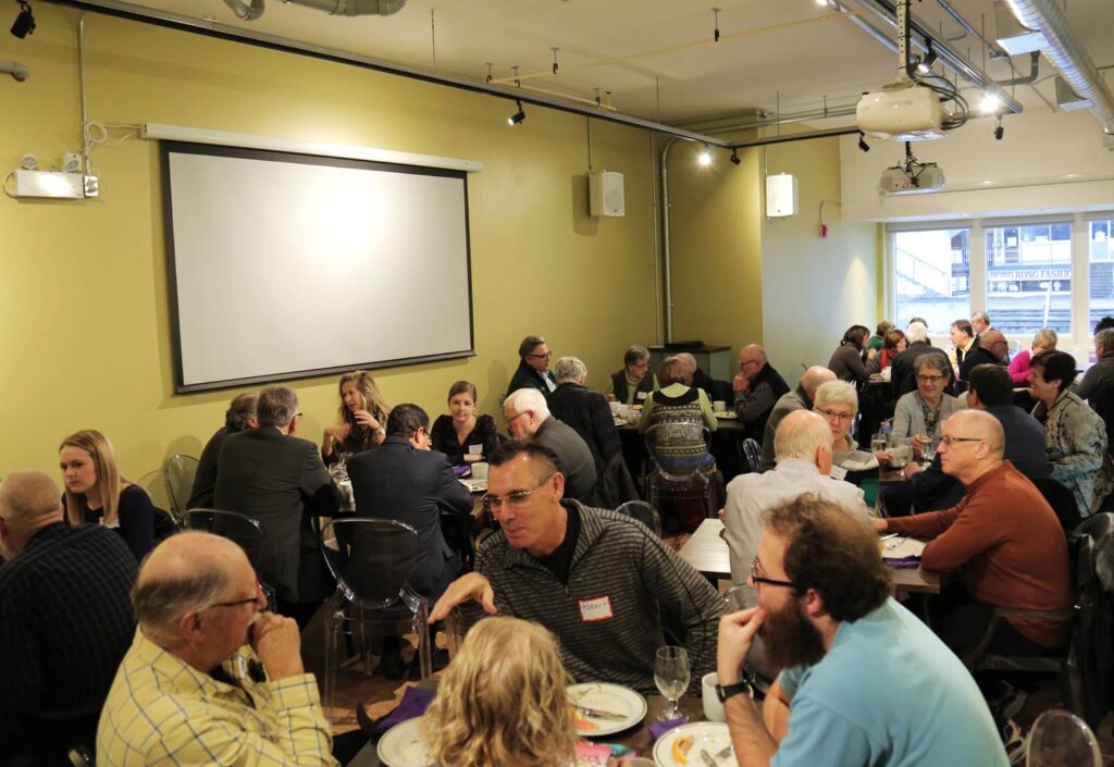 Participants engaging in discussions and enjoying a meal in the event space at Fresh Ground Café, Kitchener.