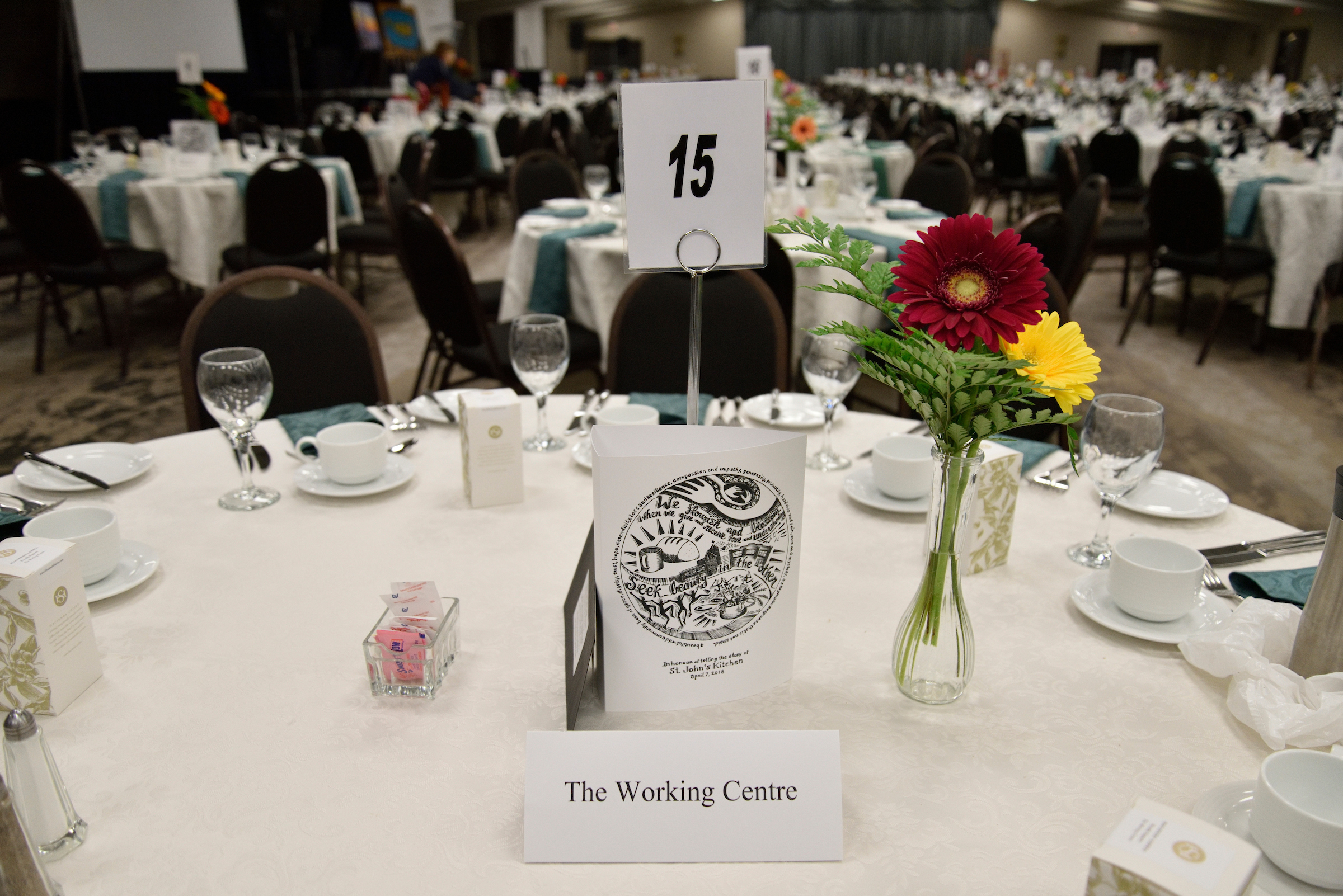 Elegant table arrangement with flowers and table number 15 at the 31st Annual Mayors' Dinner hosted by The Working Centre.