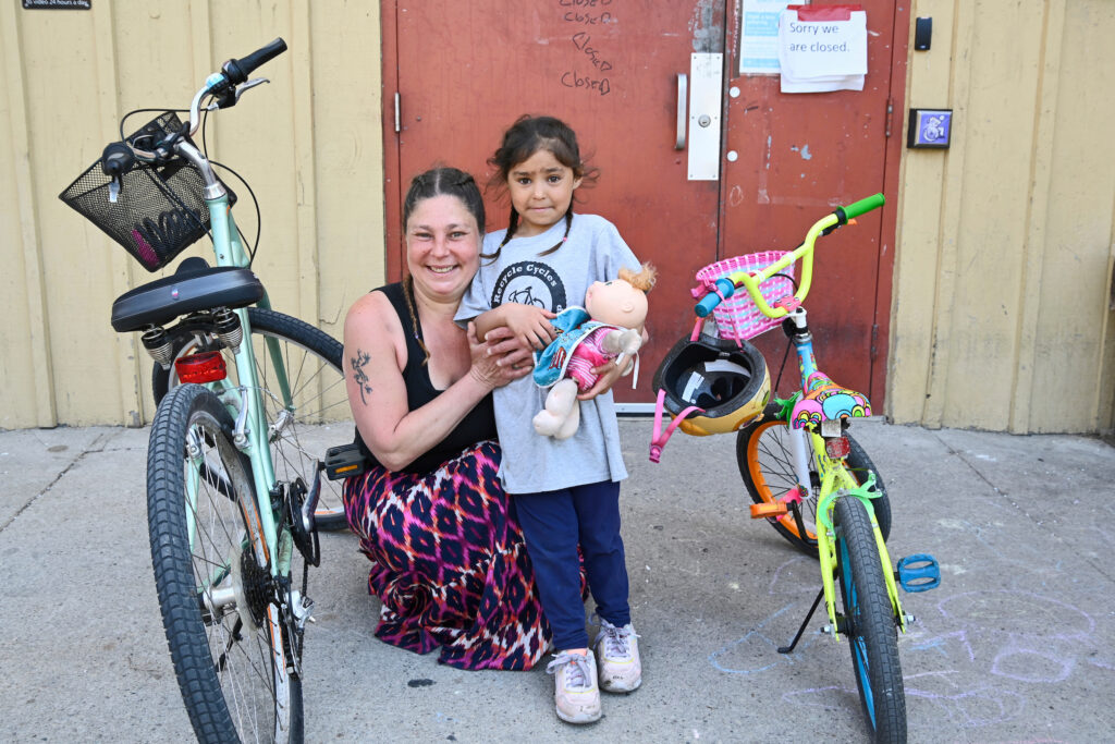 Abigail and Natalia posing with their bicycles outside Recycle Cycles in Kitchener, Ontario, April 2023.