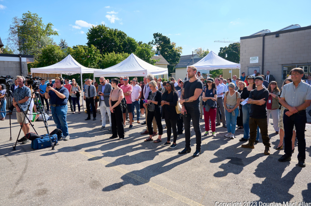 People attending an outdoor event organized by The Working Centre, with tents and media present.