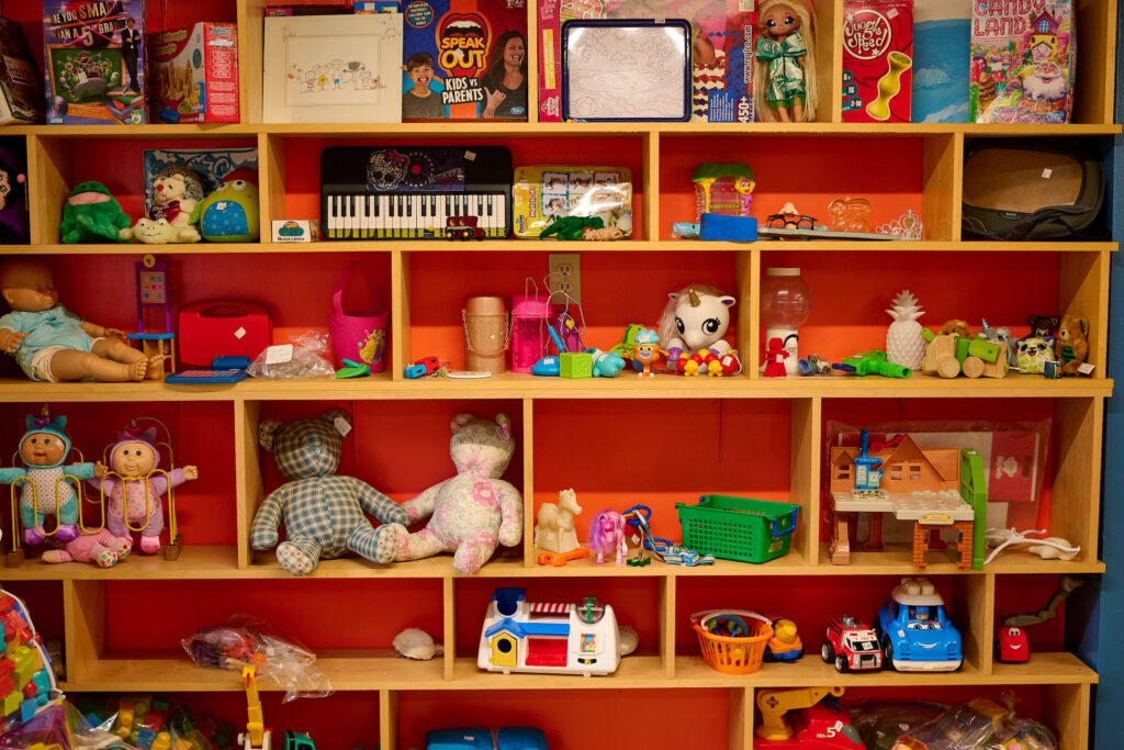 Shelves filled with colorful toys, stuffed animals, and small items at Worth a Second Look used furniture store in Kitchener, Ontario, 2024.