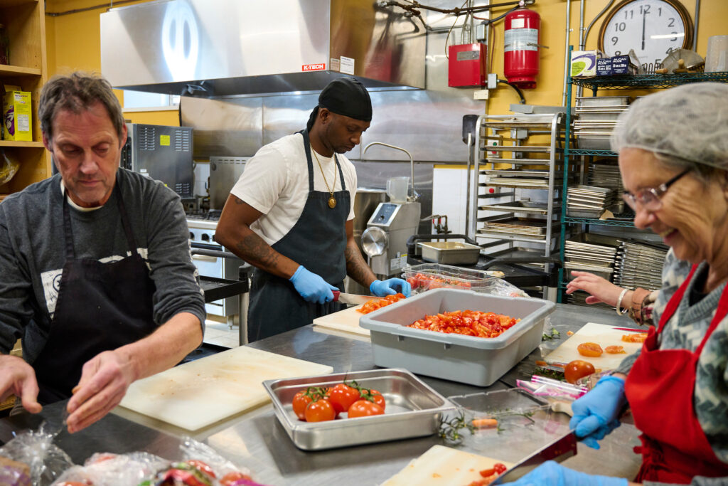 Volunteers preparing meals in the kitchen at Maurita’s Kitchen, cutting and organizing fresh produce for community meals.