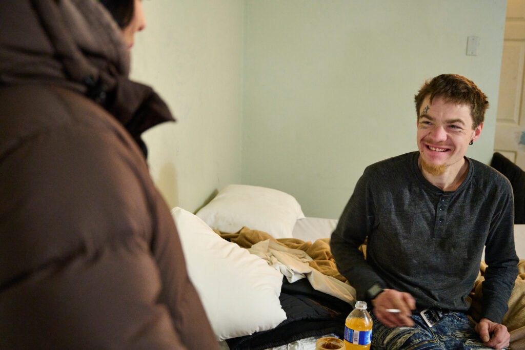 Nikki Britton, an SOS outreach worker, speaks with Alex, a long-time client, in his motel room during food bank hamper distribution in Kitchener, Ontario.