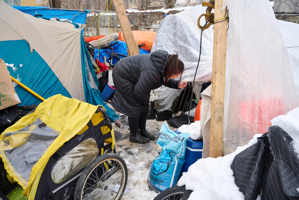 A registered nurse from the SOS team talks to a client outside a tent in a snowy encampment in Kitchener, Ontario.