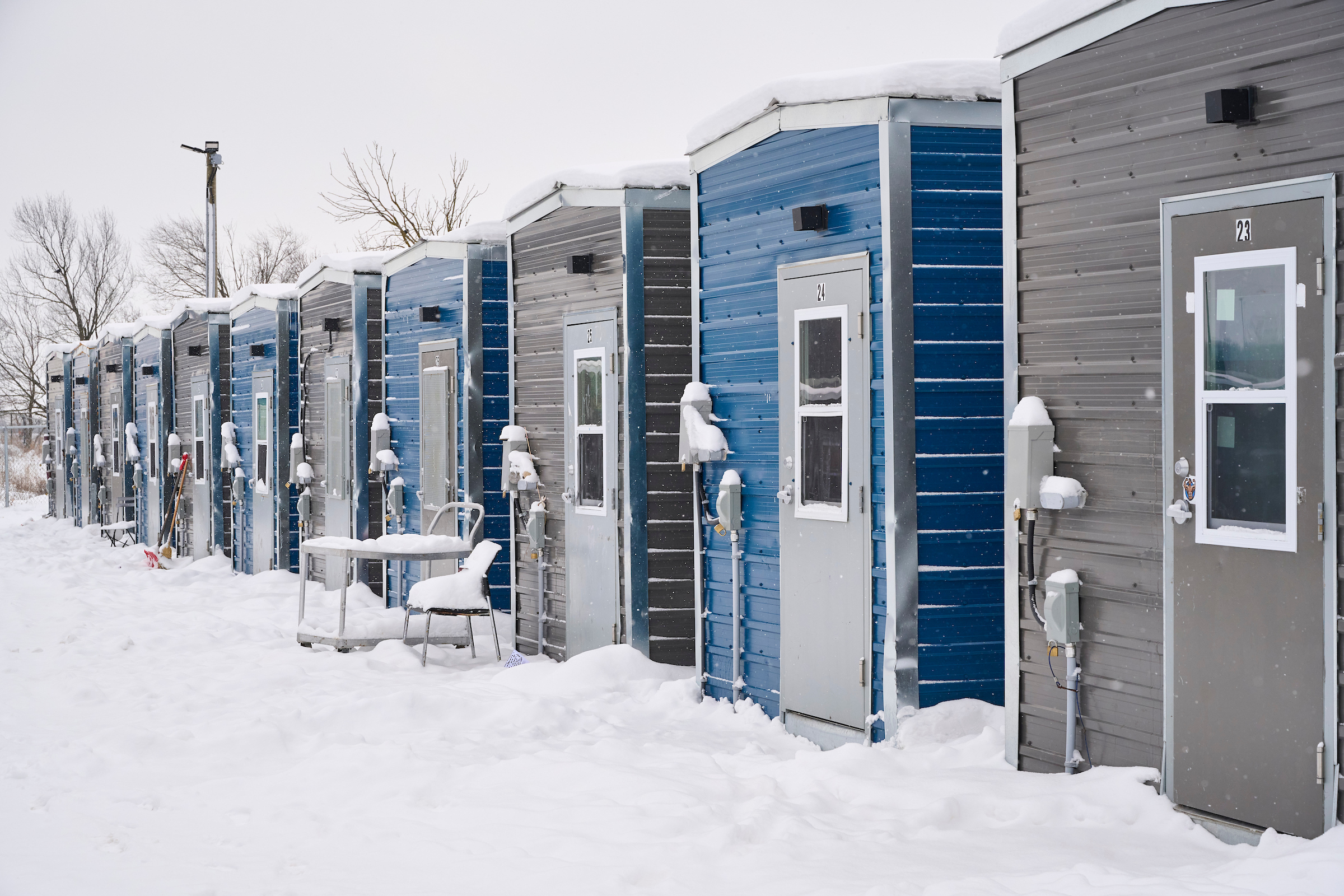 Row of colorful tiny houses made from shipping containers covered in snow at the Erbs Road Shelter compound.