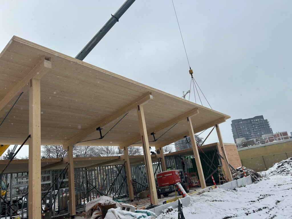 Construction of the new St. John’s Kitchen facility in progress, featuring wooden beams and snow-covered surroundings, Kitchener, Ontario, 2024.