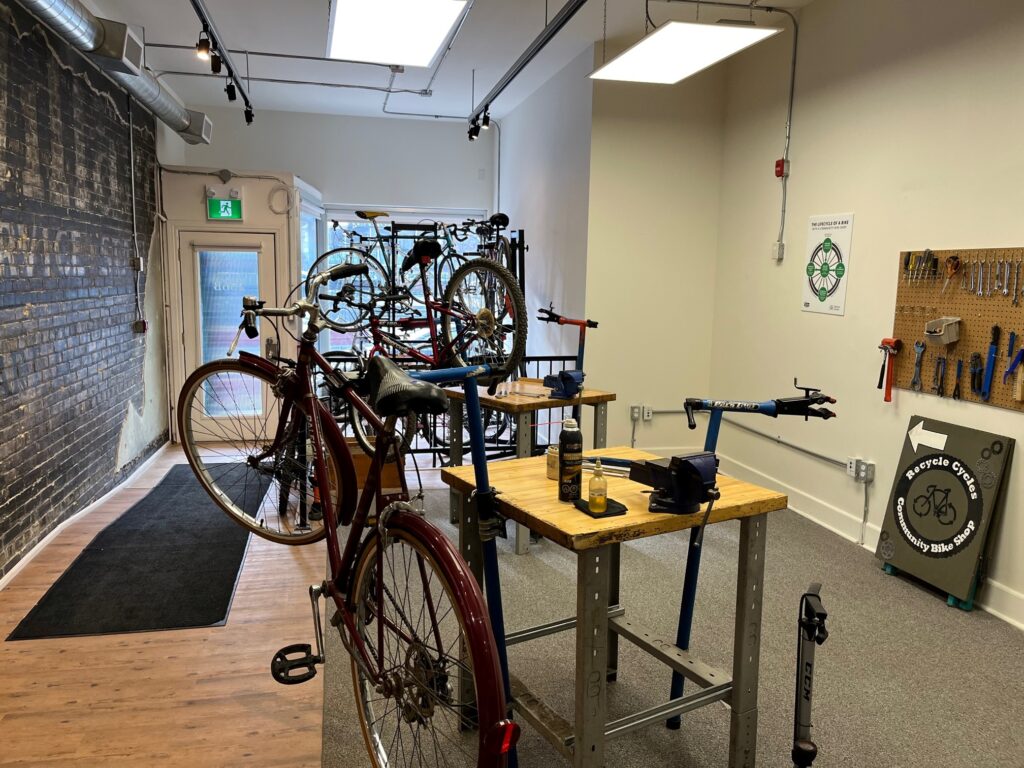 The interior of Recycle Cycles Community Bike Shop in Kitchener, featuring repair stations with bicycles and tools on display.