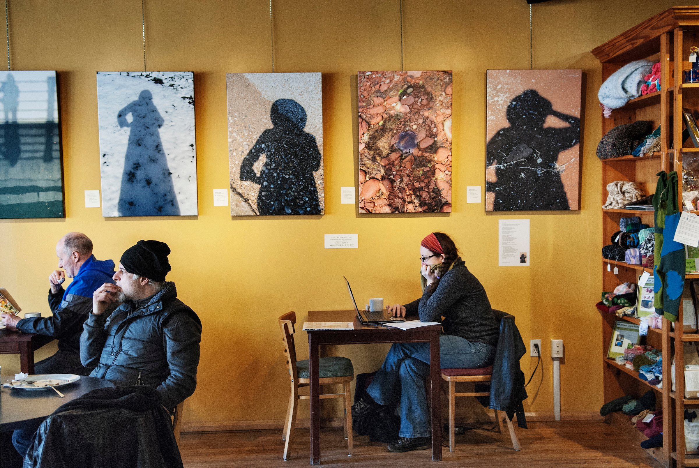 A cozy scene at The Queen Street Commons Café in Kitchener, Ontario, showing people seated at tables with vibrant artwork on the walls.