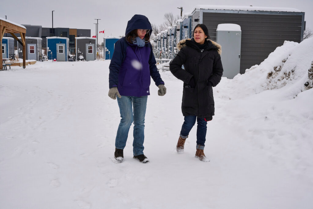 Staff person and resident walking past the cabins at Erbs Road Shelter